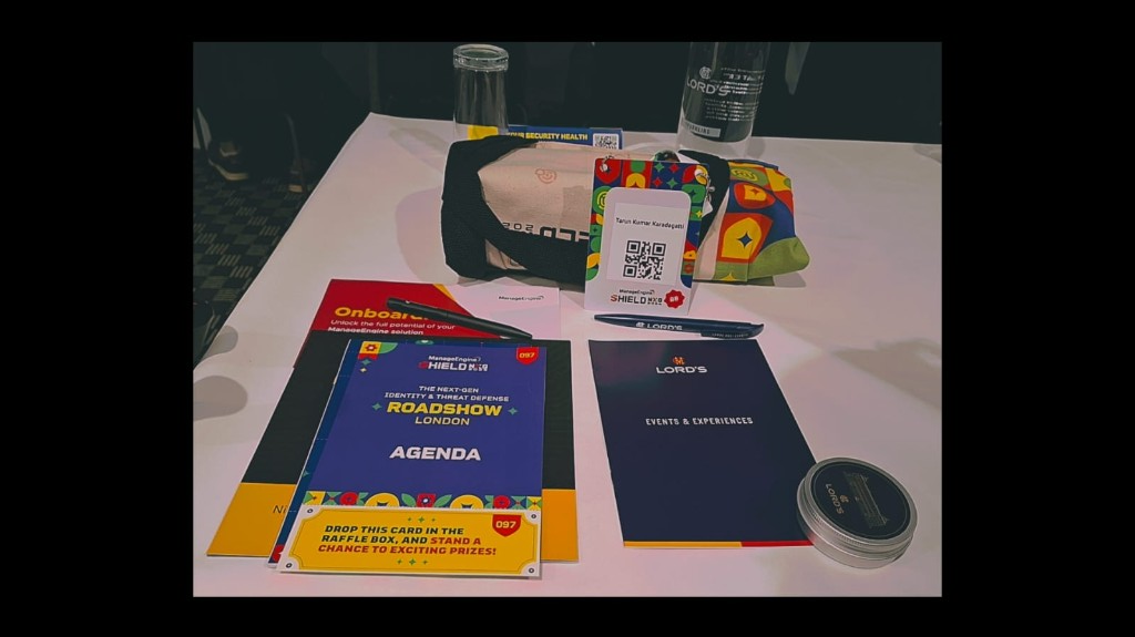 ManageEngine Shield NxG 2026 event materials at Lord's — agenda, attendee badge, raffle card, Lord's tote bag, water bottle, and commemorative tin